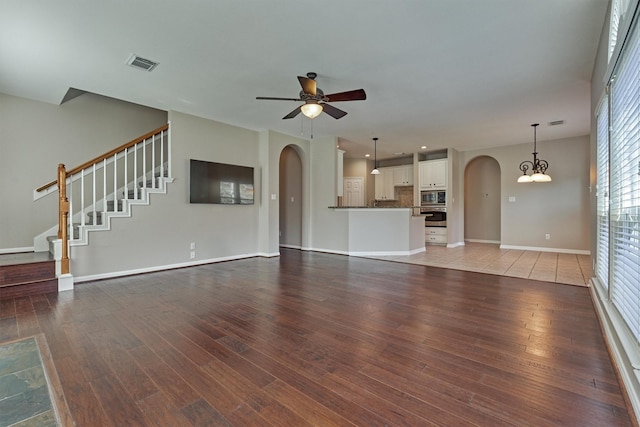 unfurnished living room featuring hardwood / wood-style floors and ceiling fan with notable chandelier