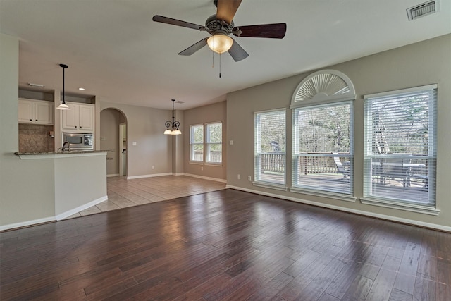 unfurnished living room with ceiling fan with notable chandelier, sink, and light hardwood / wood-style flooring