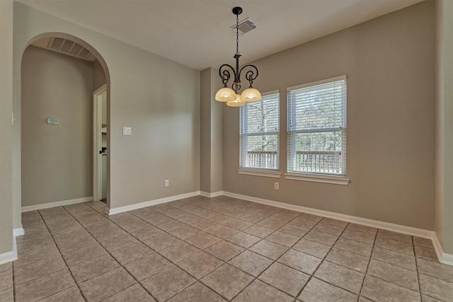 tiled spare room featuring an inviting chandelier