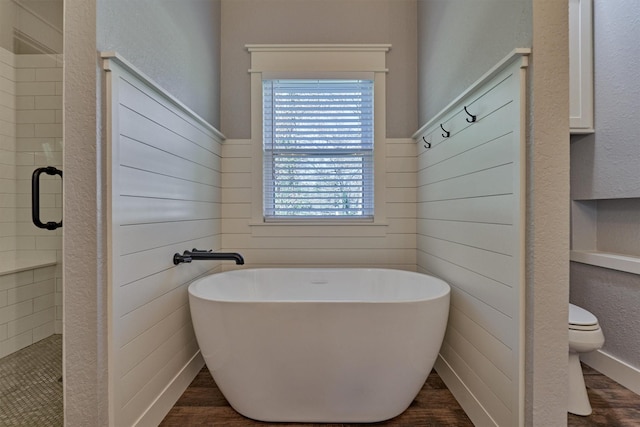 bathroom featuring shower with separate bathtub, hardwood / wood-style flooring, and toilet