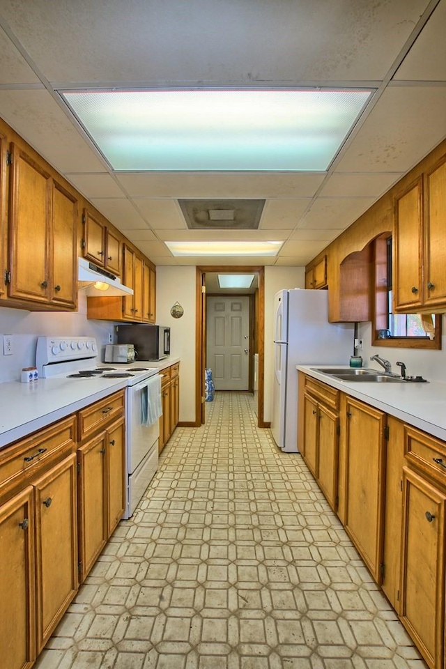 kitchen featuring a paneled ceiling, white appliances, and sink