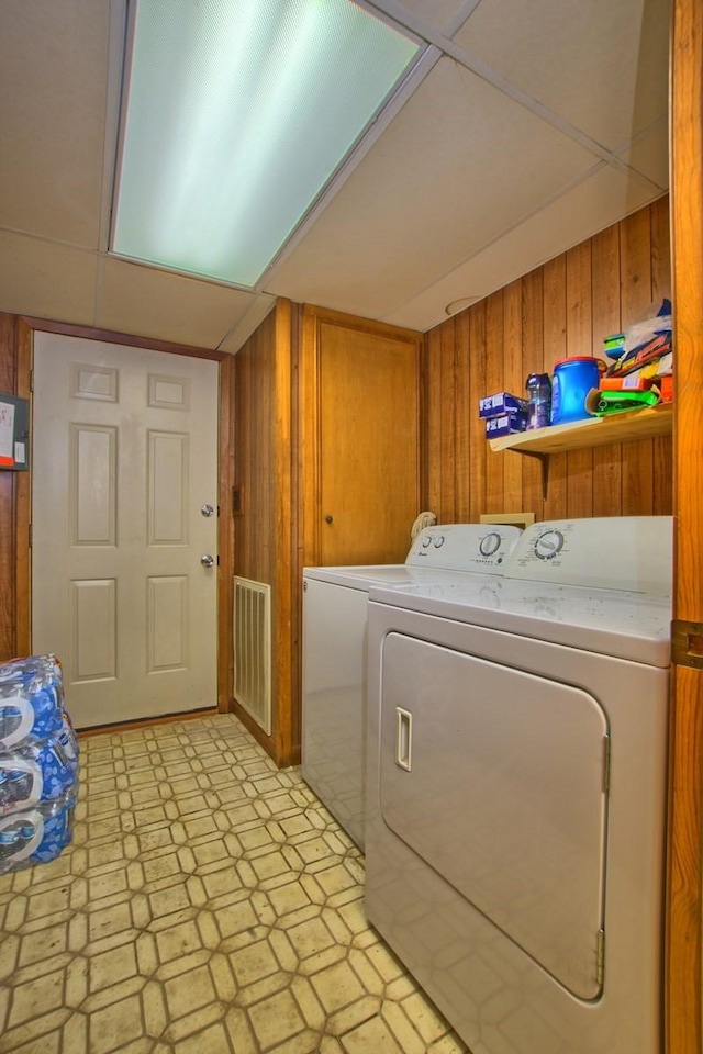 clothes washing area with wood walls and washer and clothes dryer