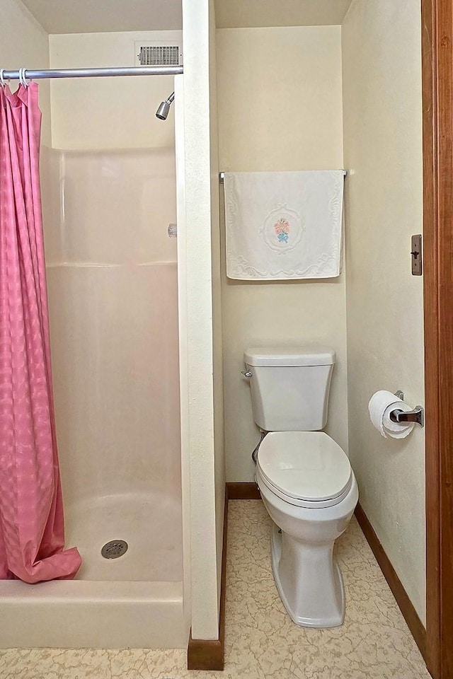 bathroom with a shower with shower curtain and toilet