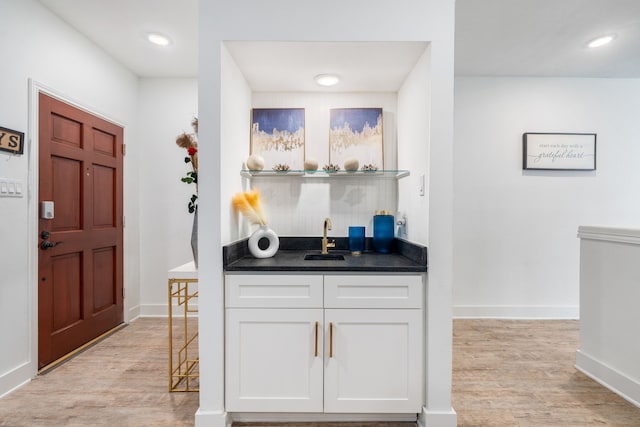 bar with white cabinets, light wood-type flooring, and sink