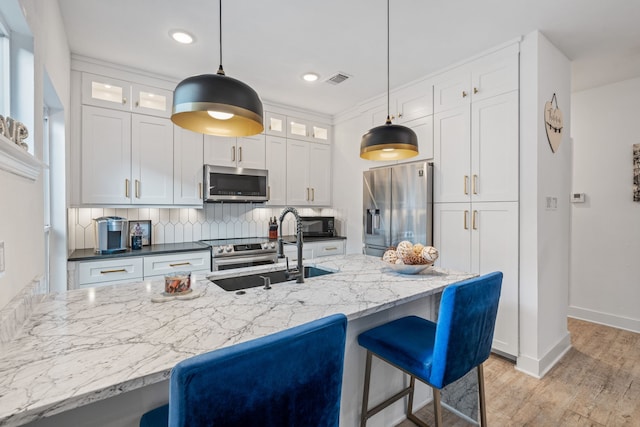 kitchen with decorative light fixtures, white cabinetry, and stainless steel appliances