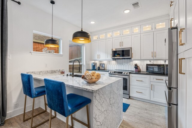 kitchen featuring white cabinets, appliances with stainless steel finishes, a breakfast bar, and decorative backsplash