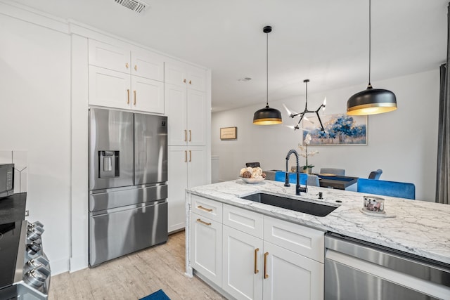 kitchen featuring white cabinets, pendant lighting, sink, and stainless steel appliances