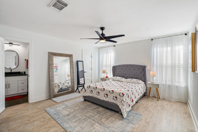 bedroom with sink, light hardwood / wood-style floors, ceiling fan, and ensuite bathroom