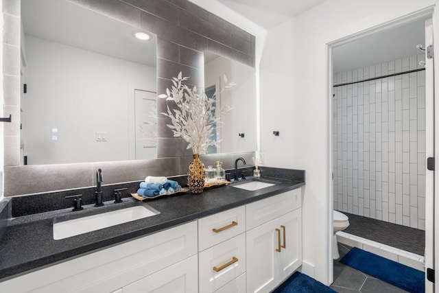 bathroom with tile patterned flooring, vanity, tiled shower, and toilet