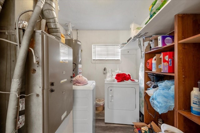 clothes washing area with hardwood / wood-style floors, washing machine and dryer, and gas water heater