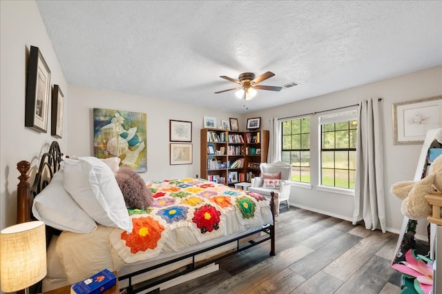 bedroom with a textured ceiling, ceiling fan, and dark hardwood / wood-style floors