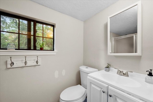 bathroom with vanity, an enclosed shower, a textured ceiling, and toilet