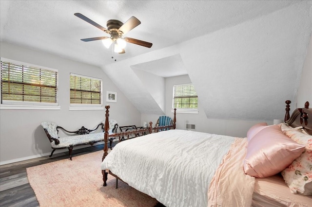 bedroom with a textured ceiling, dark hardwood / wood-style floors, vaulted ceiling, and ceiling fan