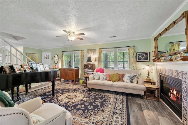 living room featuring a textured ceiling, wood-type flooring, and ornamental molding