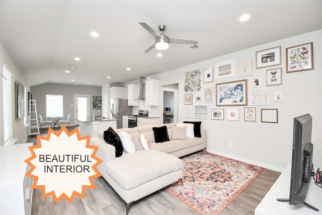 living room featuring ceiling fan, vaulted ceiling, sink, and light hardwood / wood-style flooring