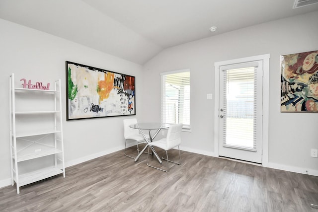 home office with wood-type flooring, lofted ceiling, and a healthy amount of sunlight