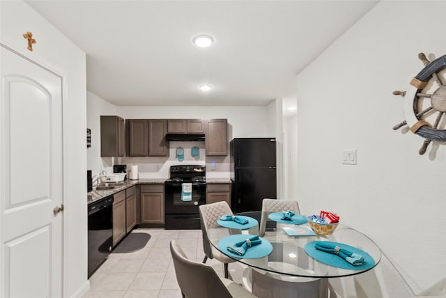 kitchen with black appliances, sink, light tile patterned floors, dark brown cabinets, and light stone counters