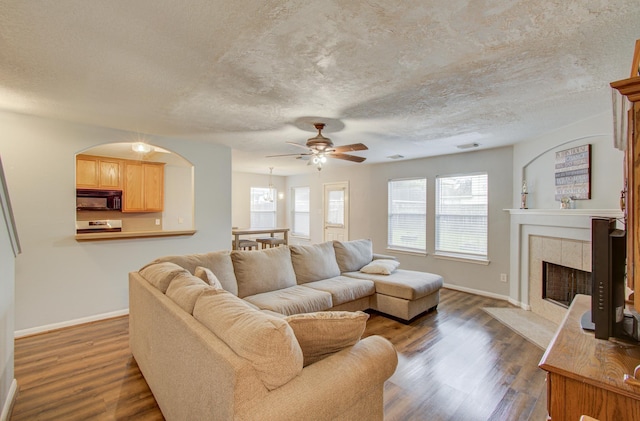 living room featuring a tile fireplace, dark hardwood / wood-style flooring, and ceiling fan