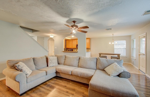 living room featuring a textured ceiling, ceiling fan with notable chandelier, and hardwood / wood-style flooring