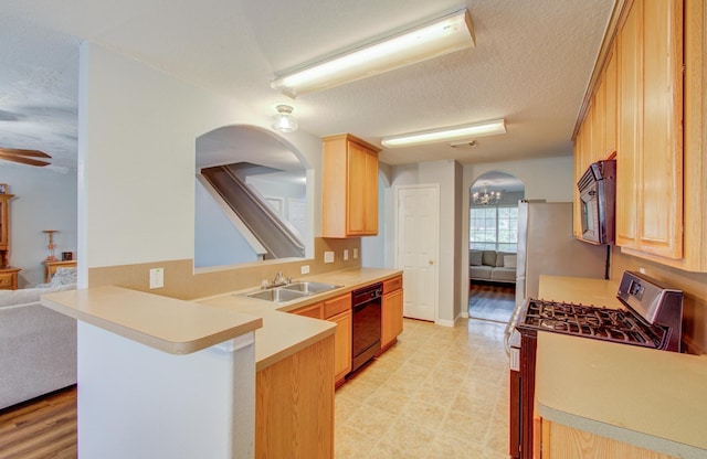 kitchen with light brown cabinets, black appliances, sink, a textured ceiling, and kitchen peninsula