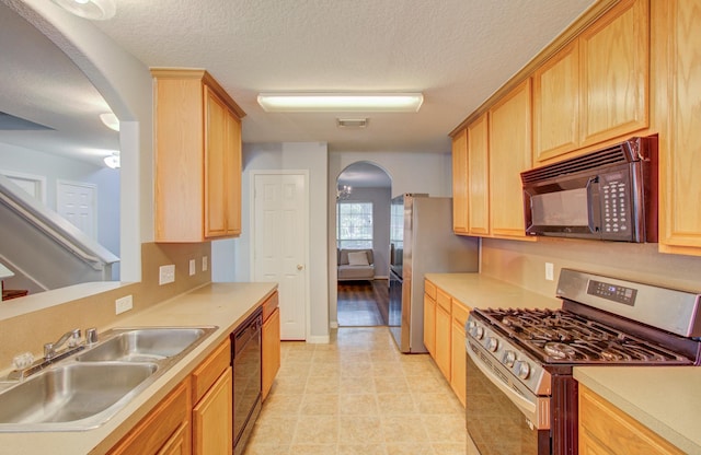 kitchen with black appliances, sink, light brown cabinetry, and a textured ceiling