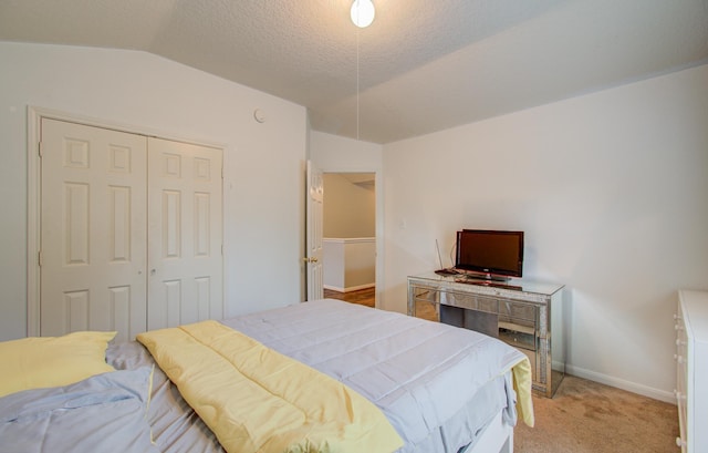 carpeted bedroom with a textured ceiling, a closet, and vaulted ceiling