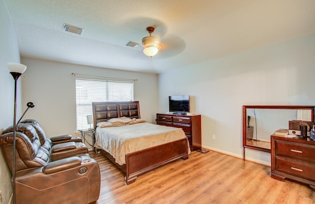 bedroom featuring ceiling fan, light hardwood / wood-style floors, and a textured ceiling