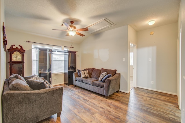 living room with ceiling fan, wood-type flooring, a textured ceiling, and vaulted ceiling