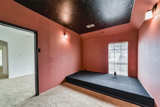 spare room featuring carpet flooring and lofted ceiling