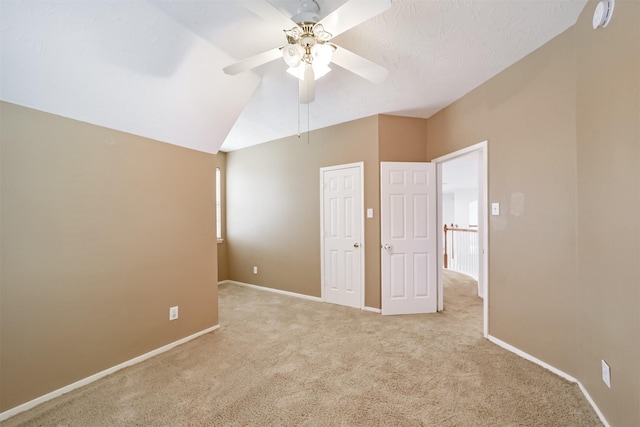 unfurnished bedroom with ceiling fan, lofted ceiling, and light carpet