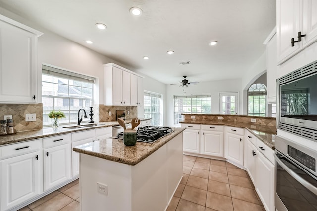 kitchen with a center island, stainless steel appliances, white cabinetry, and stone countertops