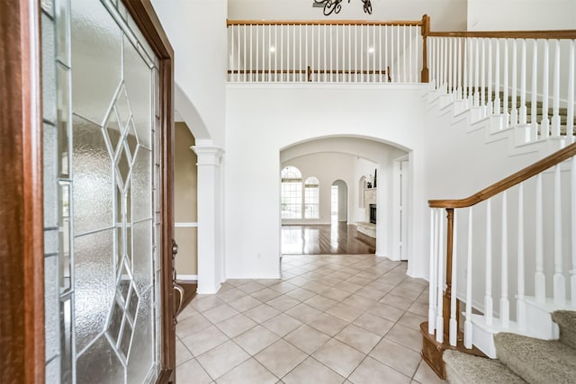 tiled foyer entrance with a tile fireplace, a high ceiling, and ornate columns