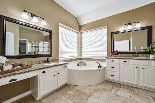 bathroom featuring tile patterned floors, vanity, lofted ceiling, and a tub to relax in