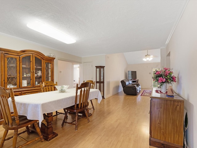 dining area featuring ceiling fan, ornamental molding, a textured ceiling, and light wood-type flooring