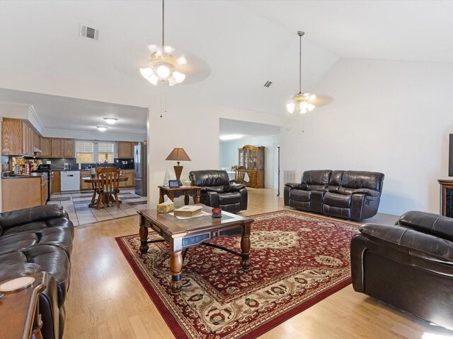 living room featuring ceiling fan, light hardwood / wood-style floors, and lofted ceiling