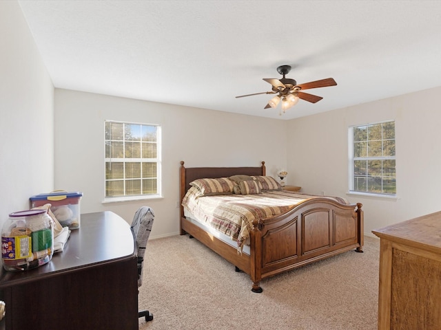 bedroom featuring ceiling fan, light colored carpet, and multiple windows