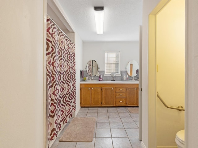 bathroom with tile patterned floors, vanity, toilet, and a textured ceiling