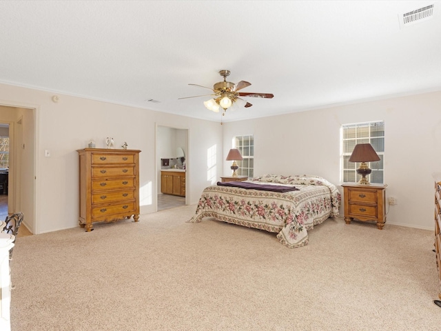 carpeted bedroom featuring ceiling fan, ensuite bath, and multiple windows