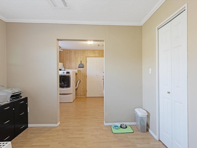 kitchen featuring wood walls, light hardwood / wood-style flooring, ornamental molding, a textured ceiling, and washer / clothes dryer