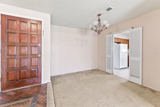 unfurnished room with a textured ceiling and a notable chandelier