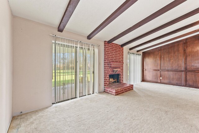 unfurnished living room with beam ceiling, light colored carpet, and a brick fireplace