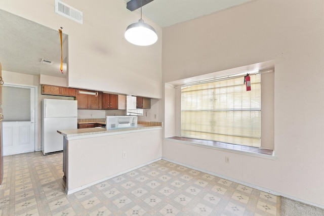 kitchen with kitchen peninsula, hanging light fixtures, and white appliances