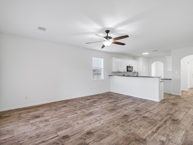 unfurnished living room with light wood-type flooring and ceiling fan