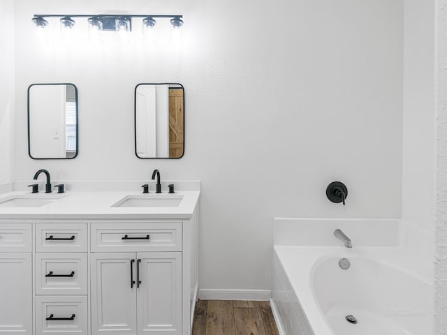 bathroom featuring vanity, tiled bath, and hardwood / wood-style flooring