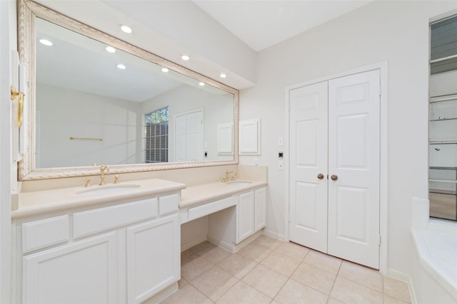 bathroom featuring tile patterned flooring, vanity, and tiled tub