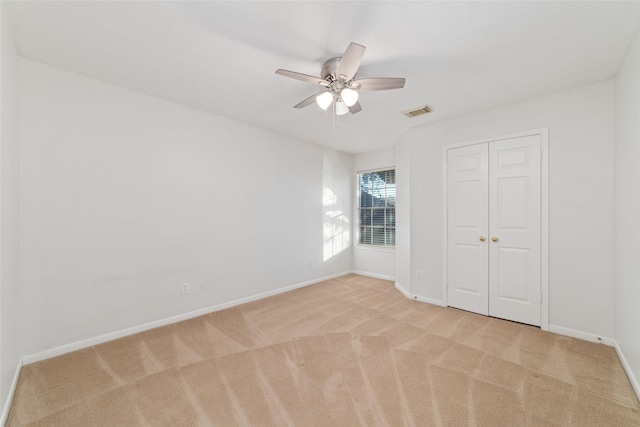 unfurnished bedroom featuring light carpet, a closet, and ceiling fan