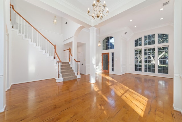 foyer entrance with a high ceiling, an inviting chandelier, french doors, crown molding, and decorative columns