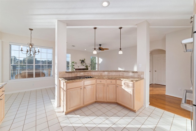 kitchen featuring light stone countertops, black stovetop, light tile patterned flooring, and ceiling fan with notable chandelier