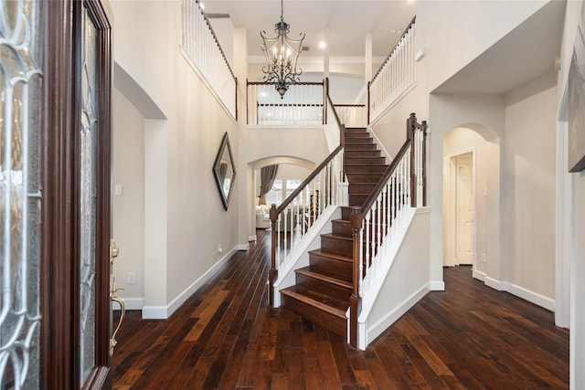 foyer entrance featuring a notable chandelier, a towering ceiling, and dark wood-type flooring