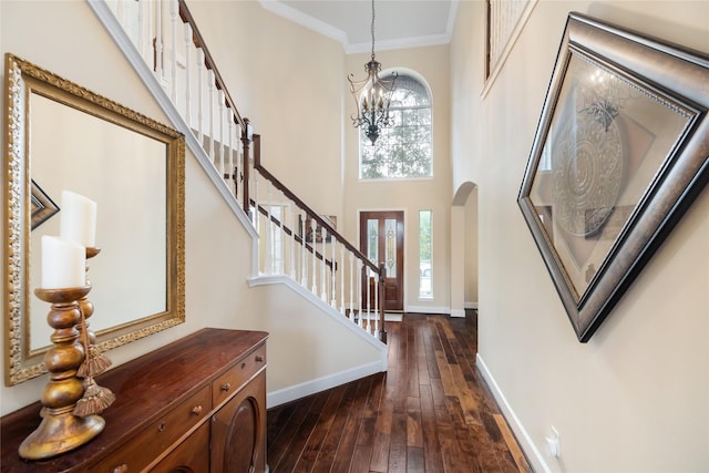 entryway featuring dark wood-type flooring, a towering ceiling, a notable chandelier, and a wealth of natural light